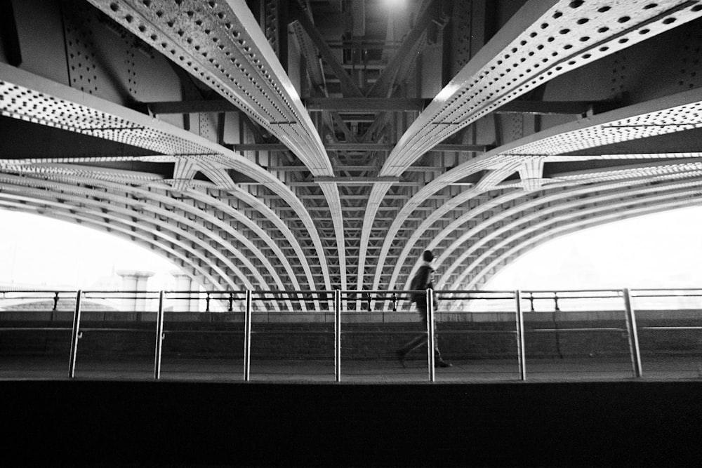 a man walking across a bridge over water