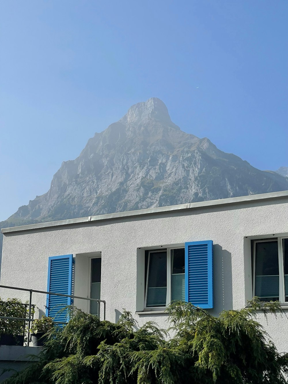 a building with blue shutters and a mountain in the background