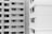 A black and white image showing the exterior of two multi-story residential buildings. One building is on the left and the other is on the right. Both buildings have numerous windows, some of which have open curtains or blinds. The architectural styles are modern with clean lines and rectangular shapes.
