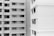 A black and white image showing the exterior of two multi-story residential buildings. One building is on the left and the other is on the right. Both buildings have numerous windows, some of which have open curtains or blinds. The architectural styles are modern with clean lines and rectangular shapes.
