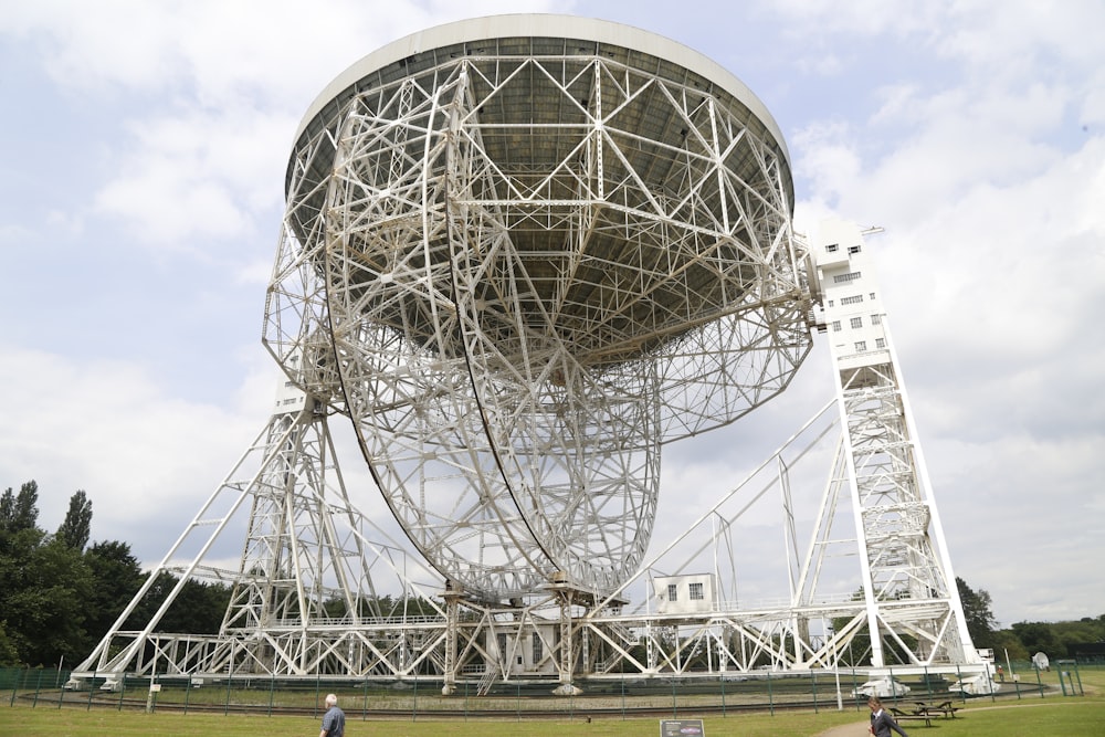 a large metal structure sitting on top of a lush green field