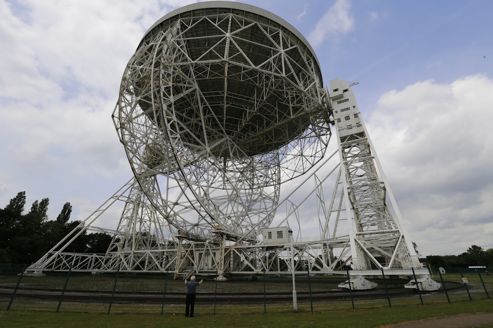 Un homme debout devant une grande antenne parabolique