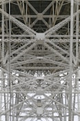 A detailed view of steel trusses forming a complex geometric pattern, showcasing industrial architecture with intersecting beams and rivets.