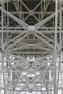 A detailed view of steel trusses forming a complex geometric pattern, showcasing industrial architecture with intersecting beams and rivets.