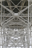 A detailed view of steel trusses forming a complex geometric pattern, showcasing industrial architecture with intersecting beams and rivets.