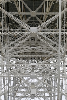 A detailed view of steel trusses forming a complex geometric pattern, showcasing industrial architecture with intersecting beams and rivets.