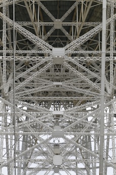 A detailed view of steel trusses forming a complex geometric pattern, showcasing industrial architecture with intersecting beams and rivets.