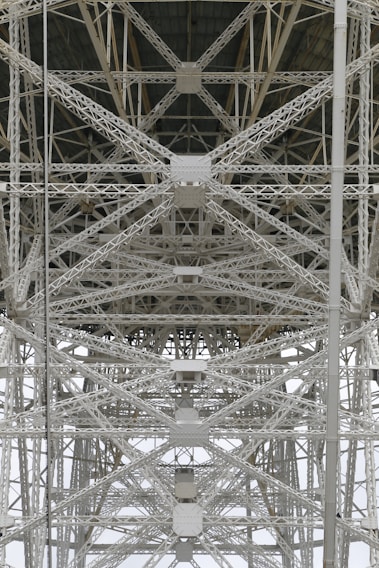 A detailed view of steel trusses forming a complex geometric pattern, showcasing industrial architecture with intersecting beams and rivets.