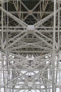 A detailed view of steel trusses forming a complex geometric pattern, showcasing industrial architecture with intersecting beams and rivets.