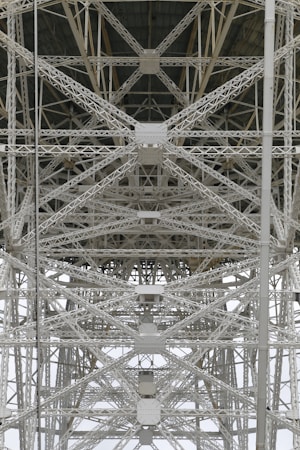 A detailed view of steel trusses forming a complex geometric pattern, showcasing industrial architecture with intersecting beams and rivets.