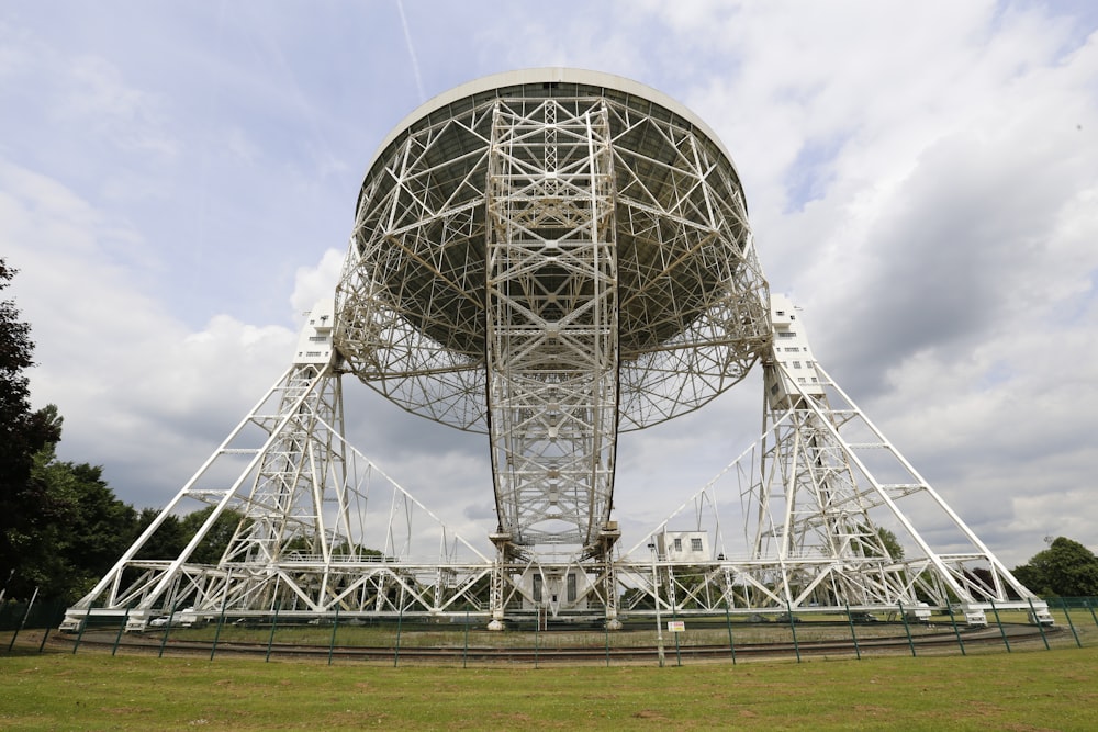 a large metal structure sitting on top of a lush green field