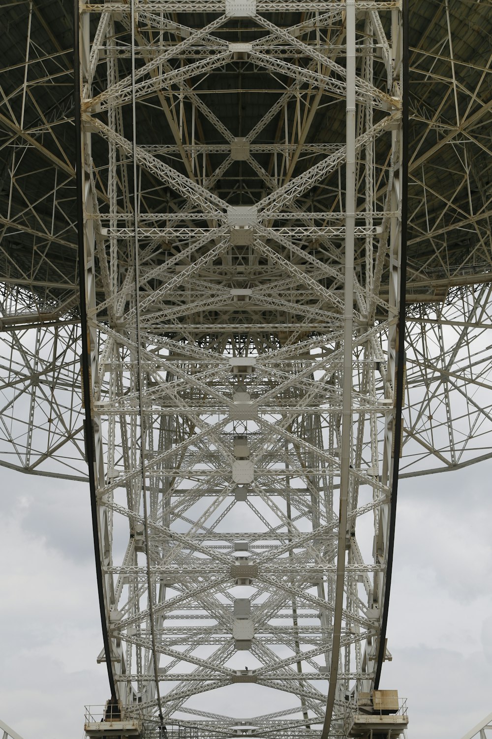 the underside of a large metal structure under a cloudy sky