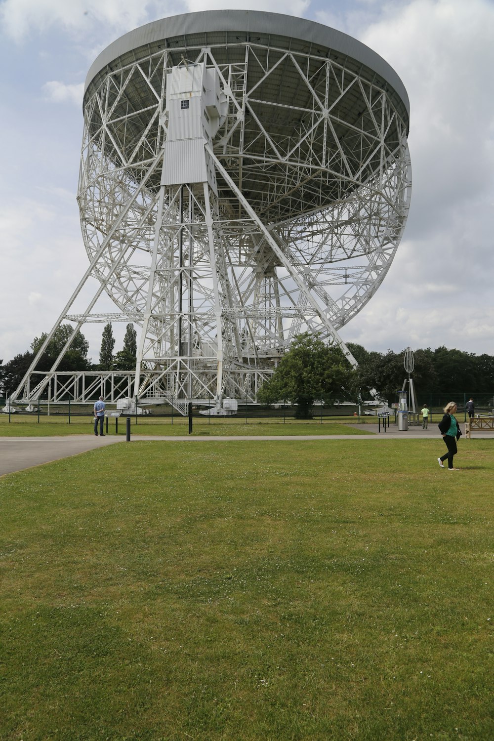 Un homme courant devant une grande antenne parabolique