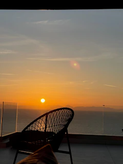 Sunset view over the calm sea from a hotel balcony with cozy seating