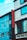 A street view of a modern building featuring a vertical red sign with the letters 'ROHAN ACC.' The building is composed of blue and gray panels with multiple windows. Power lines crisscross the scene, and part of a sign with 'GEE ESS F' is visible at the bottom.