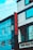 A street view of a modern building featuring a vertical red sign with the letters 'ROHAN ACC.' The building is composed of blue and gray panels with multiple windows. Power lines crisscross the scene, and part of a sign with 'GEE ESS F' is visible at the bottom.