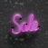 Pink neon light word 'Sale' is displayed against a textured dark background, with glow reflecting off the surface.