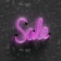 Pink neon light word 'Sale' is displayed against a textured dark background, with glow reflecting off the surface.