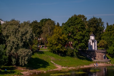 A peaceful green park area with walking paths and a small chapel in the background