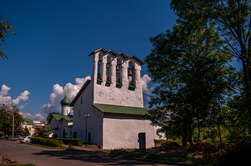 a white church with a green steeple on a sunny day