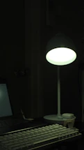 A cozy workspace with a glowing LED desk lamp illuminating a contact form on a laptop screen.