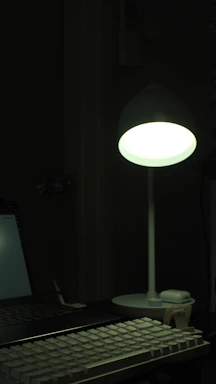 A cozy workspace with a glowing LED desk lamp illuminating a contact form on a laptop screen.