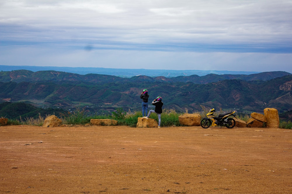 a couple of people standing on top of a dirt field