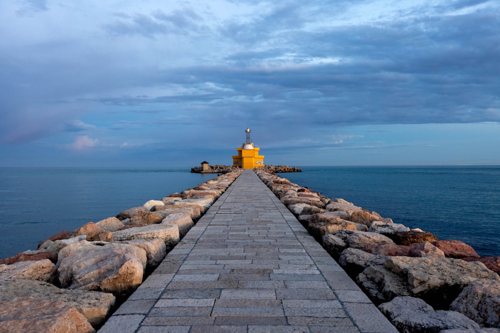 a yellow lighthouse sitting on top of a pier next to the ocean