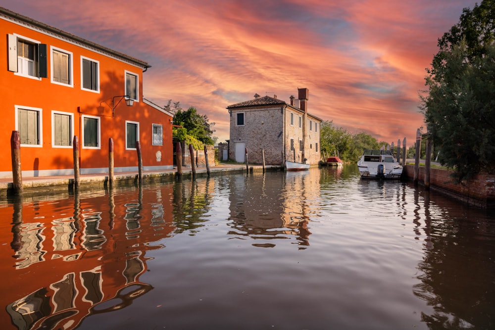 a boat traveling down a river next to a red building