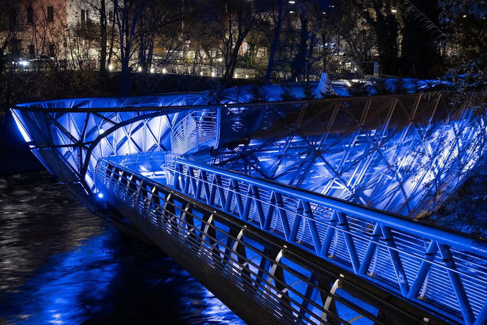 a blue lit bridge over a river at night