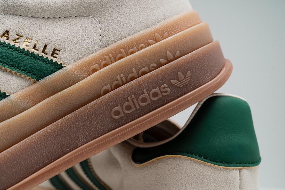 a pair of white and green sneakers with gold lettering