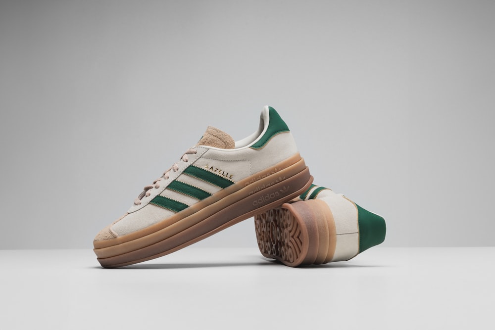a pair of white and green adidas sneakers