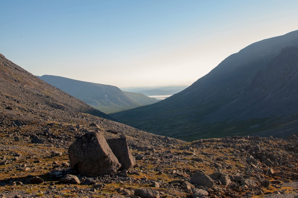 a large rock sitting on the side of a mountain