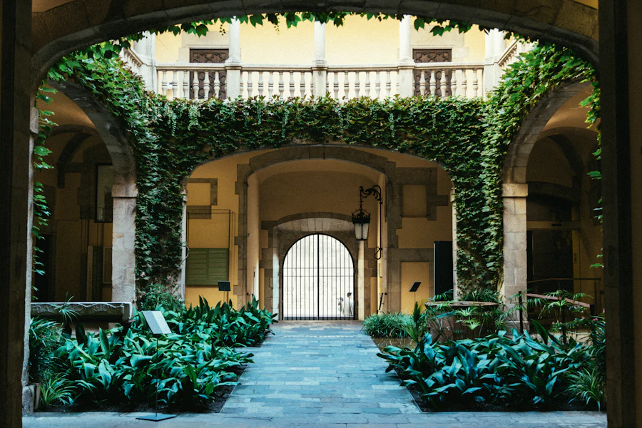 Covered cloister walk with planted courtyard and arches framing a bright doorway