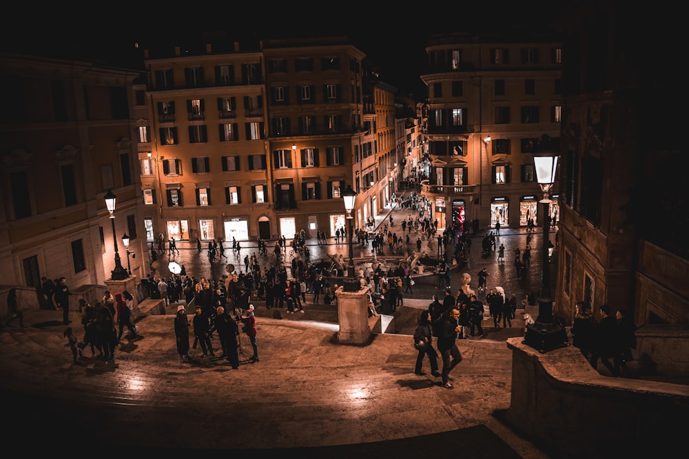 a group of people standing around a fountain at night