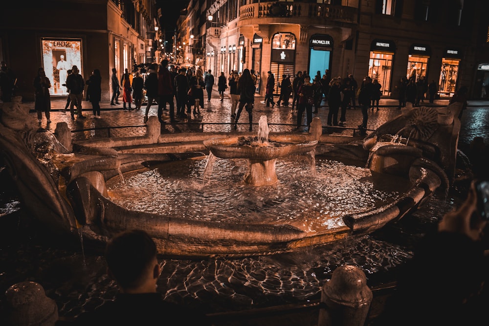 a group of people standing around a fountain