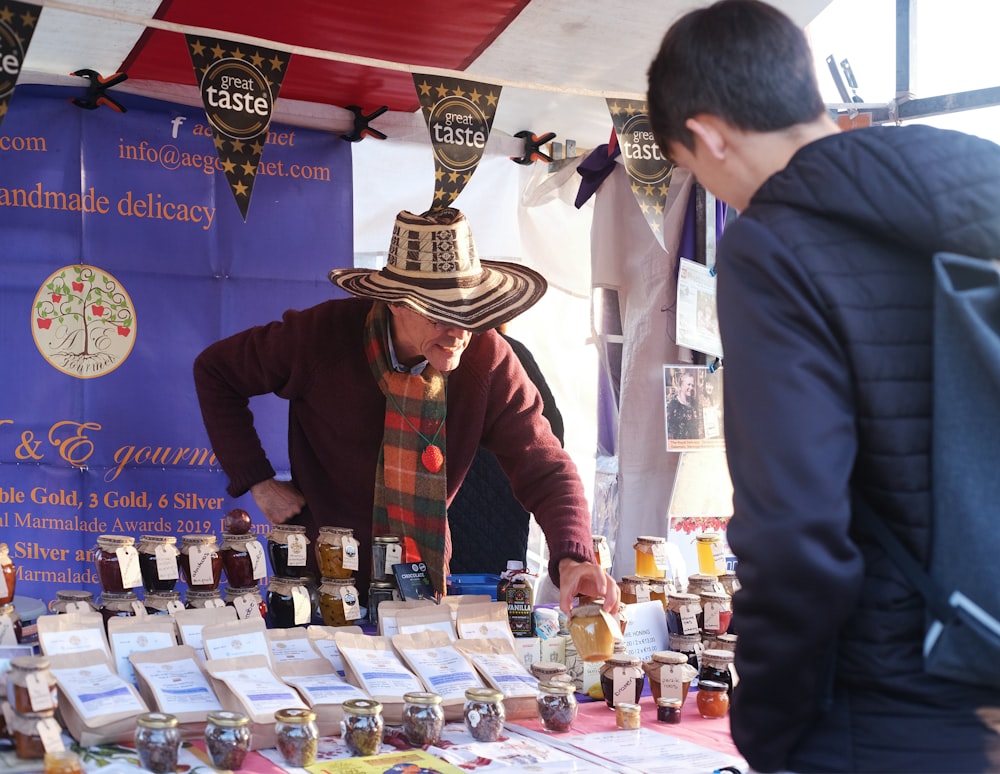a man wearing a sombrero standing next to a table filled with jars of