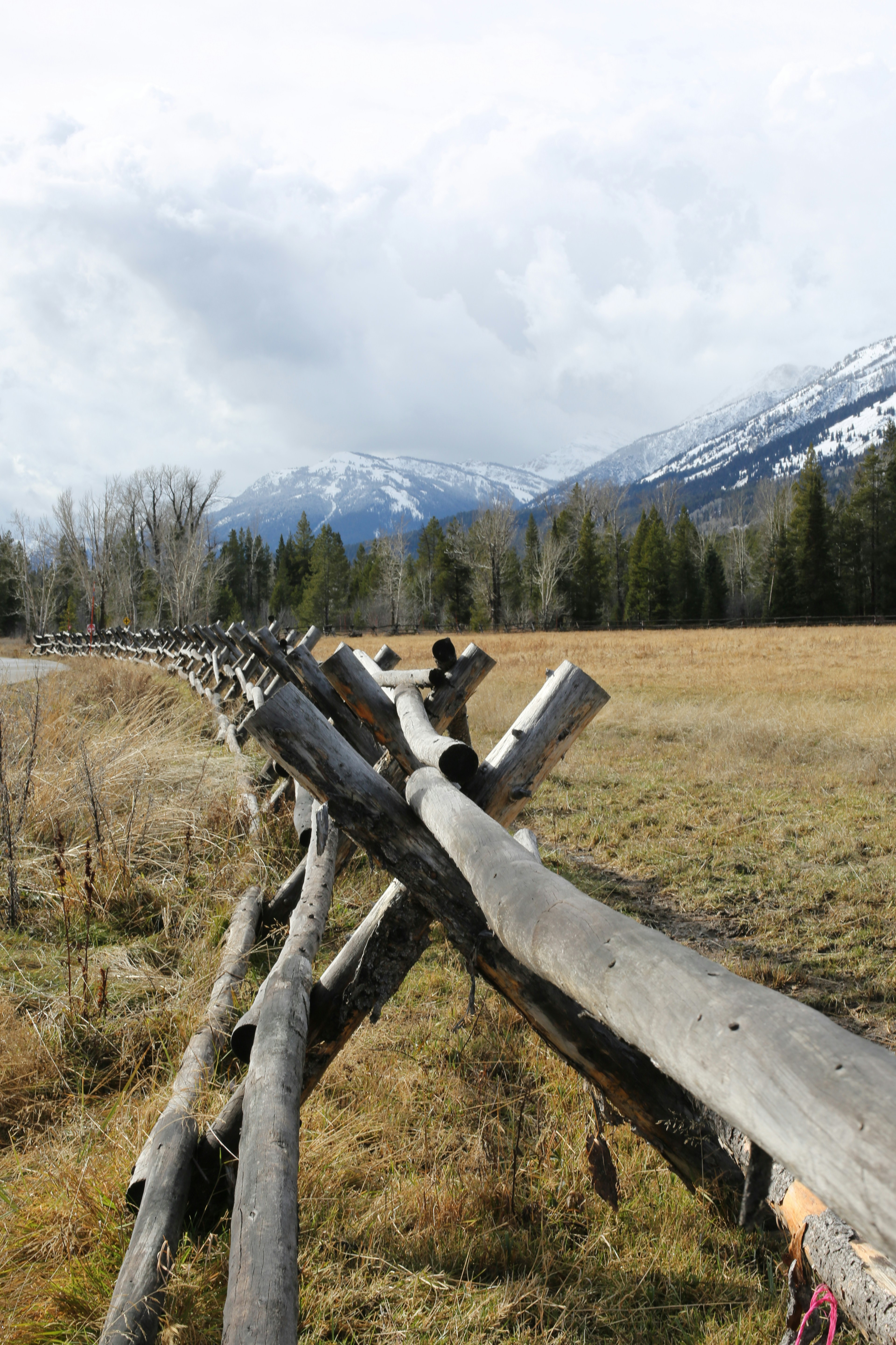 a wooden fence in a field with mountains in the background