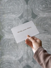 a person holding a piece of paper with writing on it
