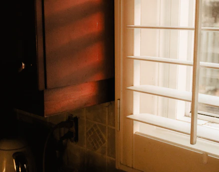Sunset light streaming through a spotless kitchen window, highlighting gleaming countertops.