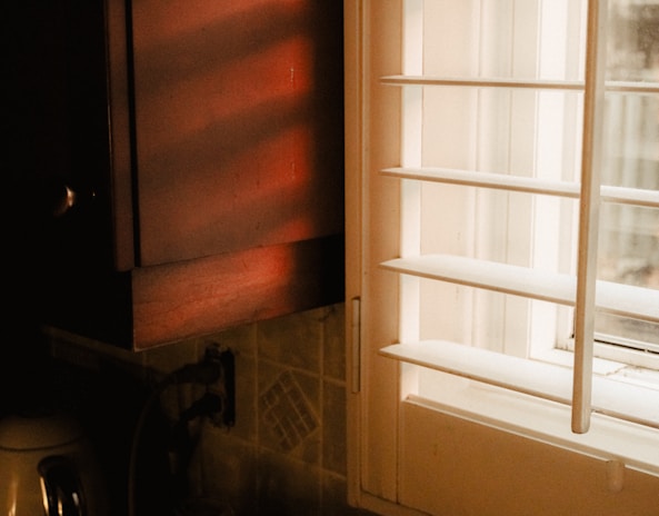 Technician testing electrical outlets in a bright kitchen with natural light streaming in.