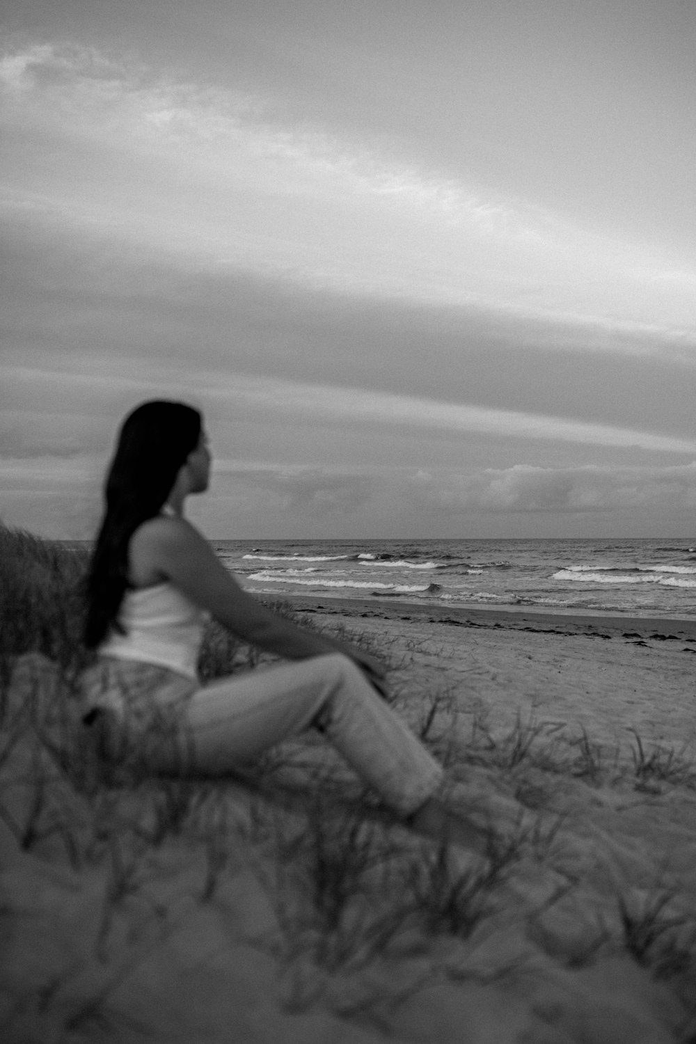 a woman sitting on a beach next to the ocean