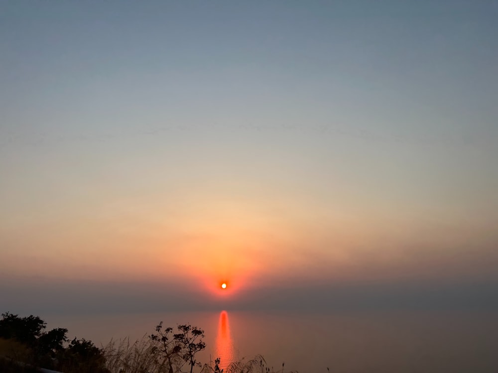 the sun is setting over the horizon of a foggy sky