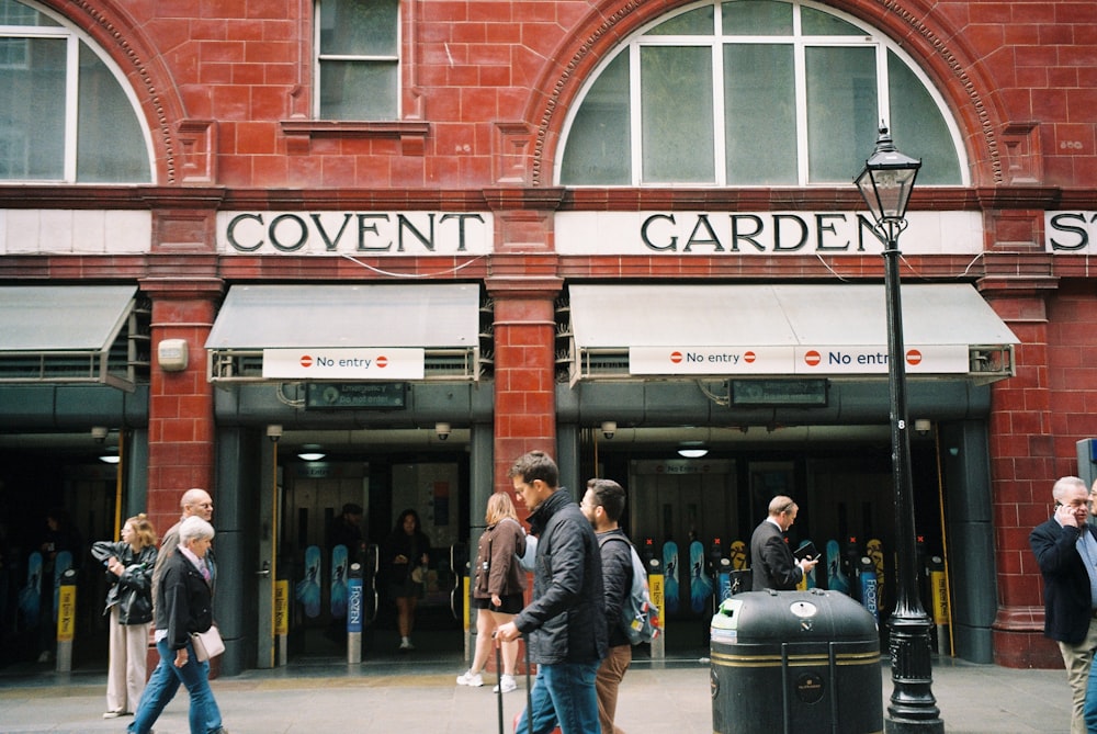 a group of people walking past a red brick building