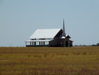 Volunteers building a new church facility in a rural village under a clear blue sky.