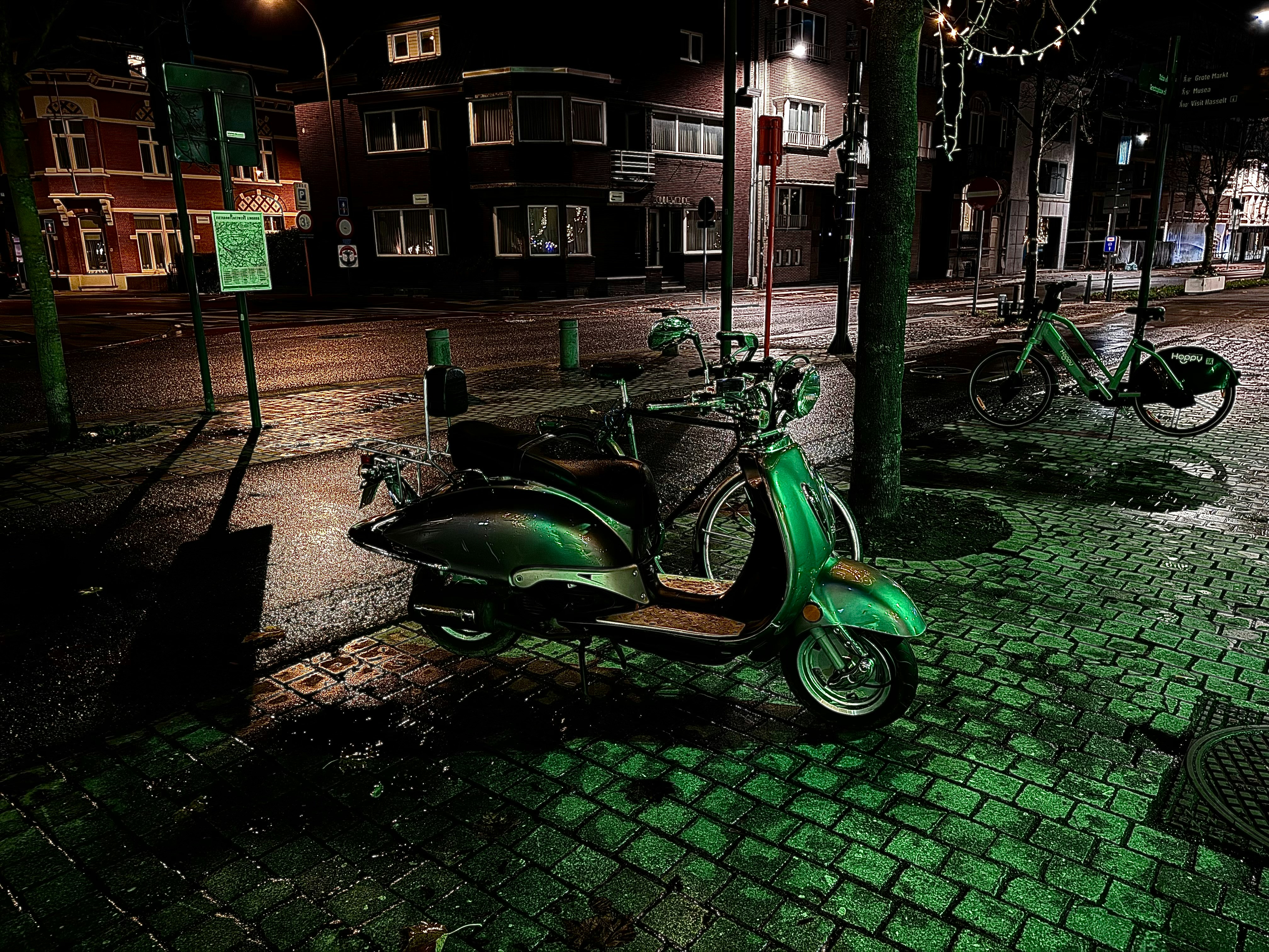 a green scooter parked on the side of a street