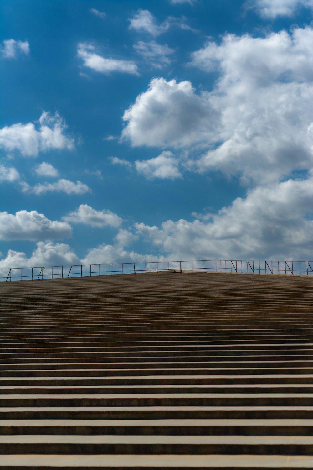 a bench sitting on top of a hill under a cloudy blue sky