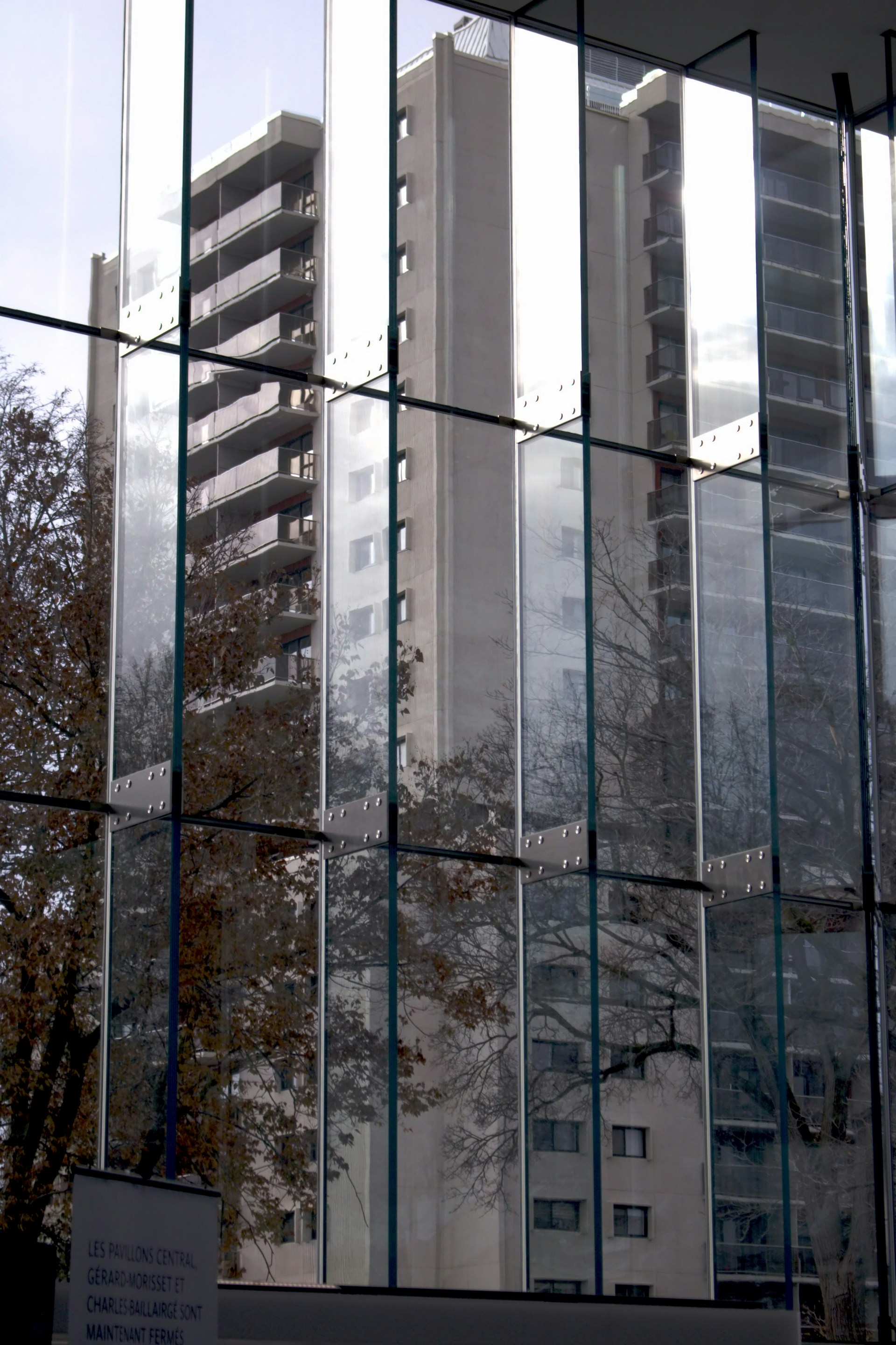 a tall building reflected in the windows of another building