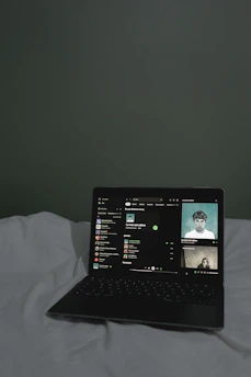 A collection of music tracks displayed on a laptop screen with headphones nearby.