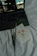 A laptop on a bed displays a music streaming platform with album art and song details. Next to it are a few paintbrushes and a card featuring a watercolor painting of pink flowers and green stems.